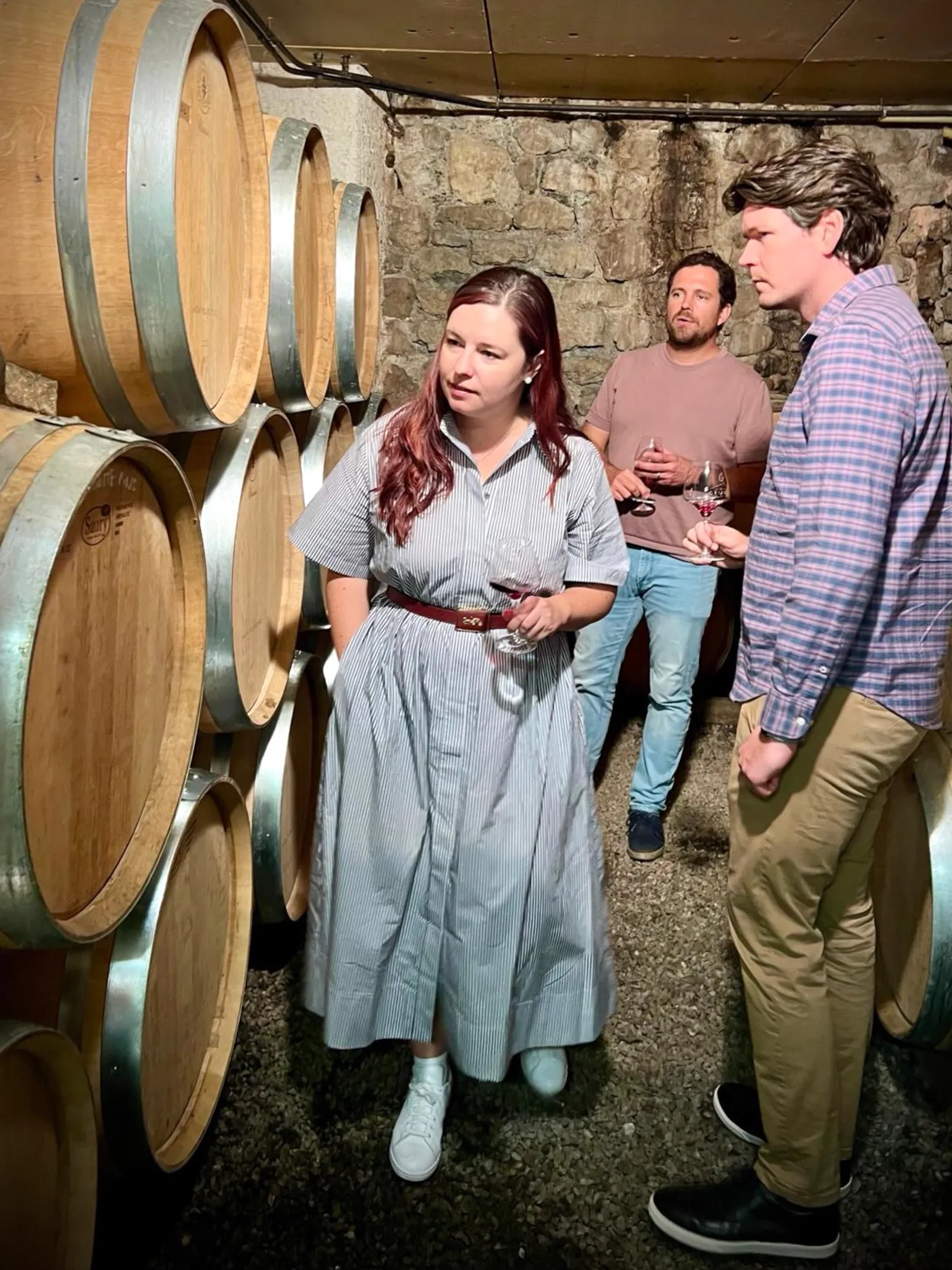 Private visit to a Savoie cellar: guests tasting red wine among oak barrels and old stone walls