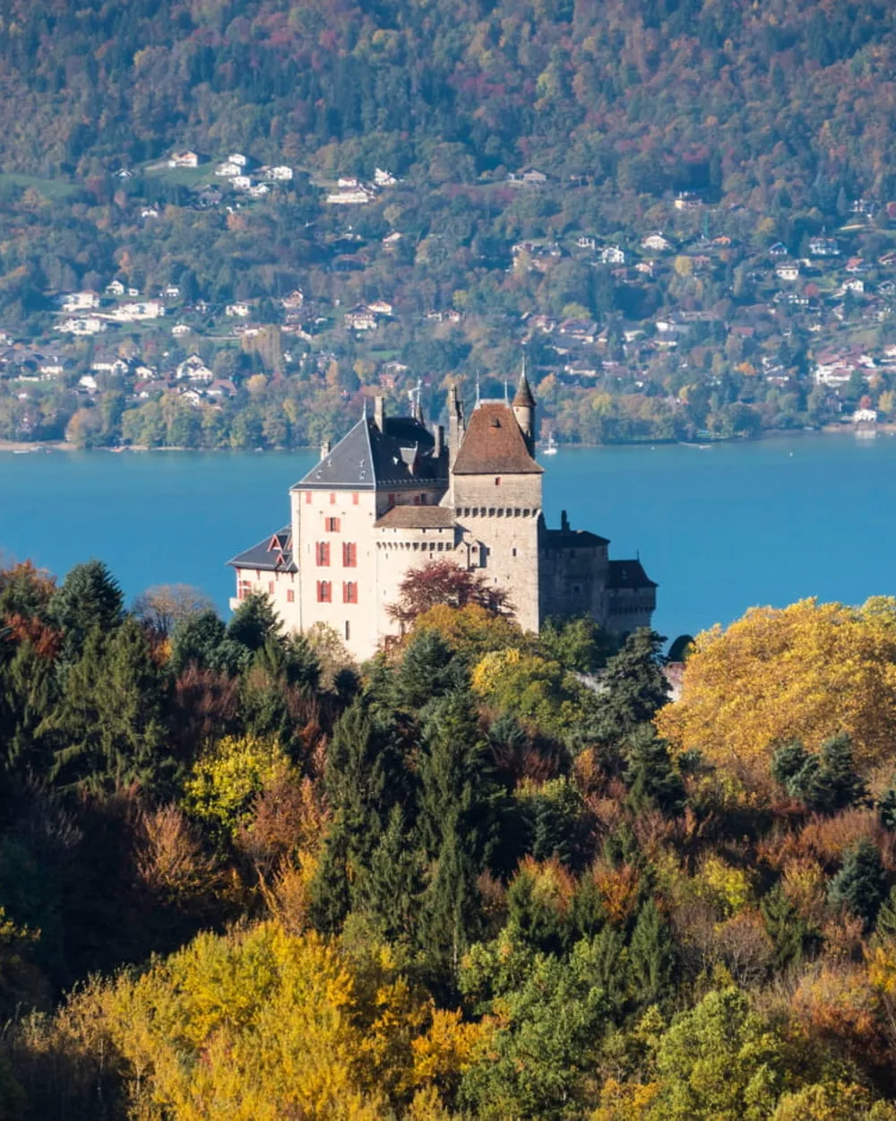 Château de Menthon-Saint-Bernard rising above autumn forests on the shores of Lake Annecy