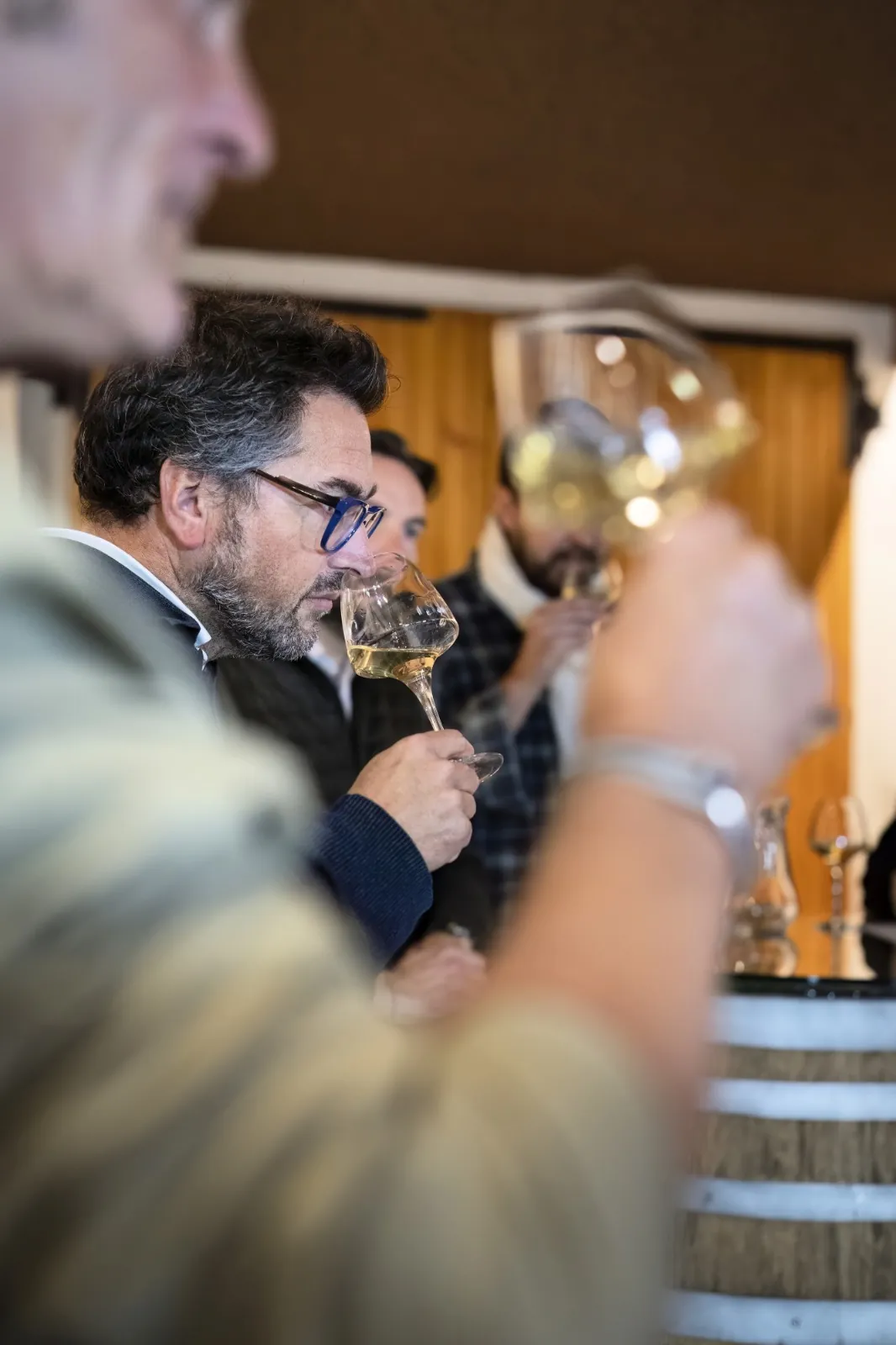 A winemaker pouring a glass of Savoie white wine during a private cellar tasting, soft natural light